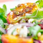 Close up peach and feta cheese salad with puy lentils and rocket or arugula featuring a title overlay.