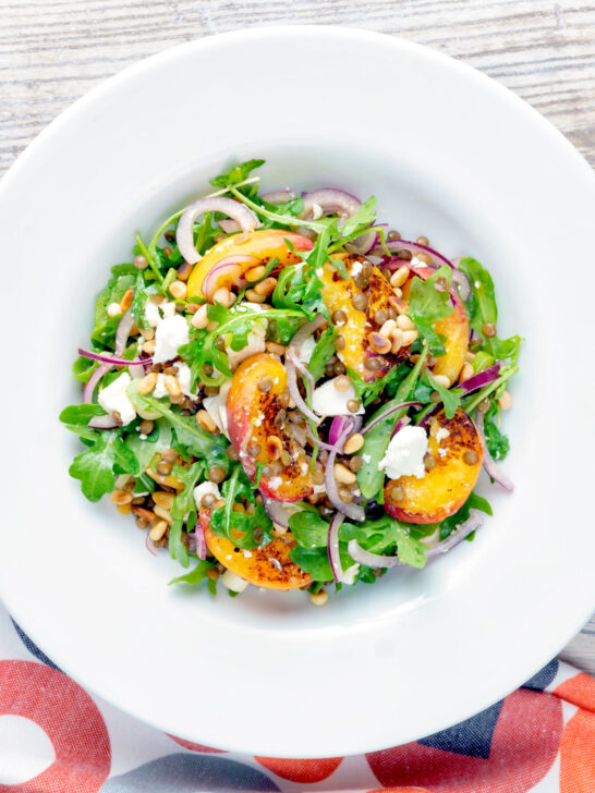 Overhead peach and feta cheese salad with puy lentils and rocket or arugula.