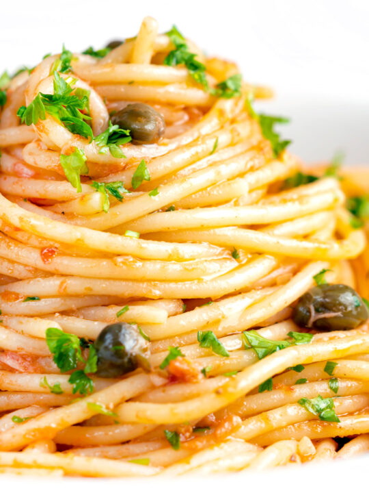 Close up tomato tuna pasta with capers and fresh parsley.