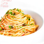 Tomato tuna pasta with capers and fresh parsley featuring a title overlay.