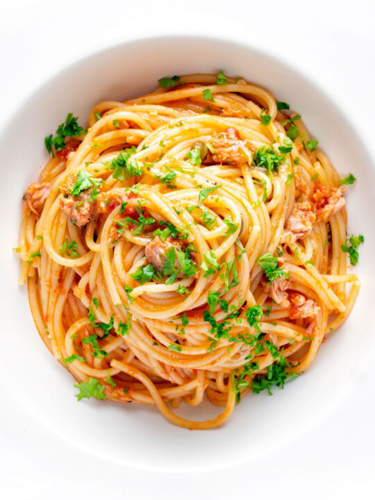 Overhead tomato tuna pasta with capers and fresh parsley.