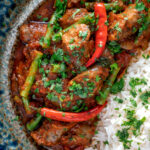 Close up overhead Indian inspired beef sausage curry served with rice featuring a title overlay.