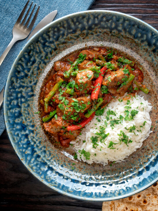 Overhead Indian inspired beef sausage curry served with rice.