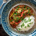 Overhead Indian inspired beef sausage curry served with rice featuring a title overlay.