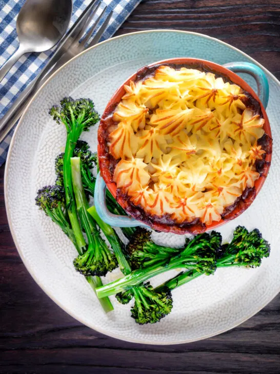 Overhead sausage and mash pie served with roasted tenderstem broccoli.