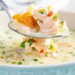 Close up of a spoonful of slow cooker salmon chowder featuring a title overlay.