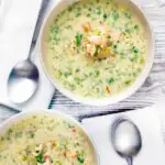 Overhead of two bowls of slow cooker salmon chowder featuring a title overlay.