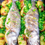 Baked or roasted sea bass with new potatoes, peas, broad beans and bacon.