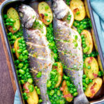 Overhead baked or roasted sea bass with new potatoes, peas, broad beans and bacon.