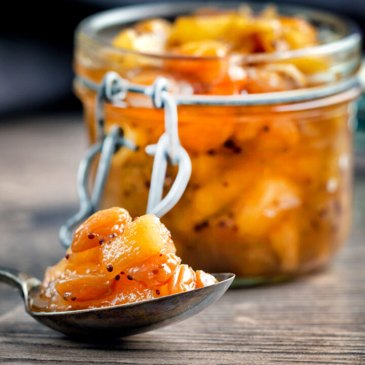 Close up apple chutney with golden raisins on a spoon.