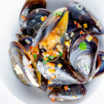 Overhead beer steamed mussels with shallot, chilli and garlic.