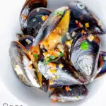 Overhead beer steamed mussels with shallot, chilli and garlic featuring a title overlay.