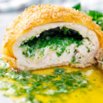 Close up golden chicken Kyiv cut open showing garlic butter filling.