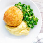 Overhead golden chicken Kyiv served with mashed potato.