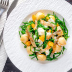 Overhead cod fish salad with asparagus, samphire, new potatoes and orange featuring a title overlay.