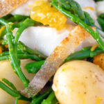 Close up cod fish salad with asparagus, samphire, new potatoes and orange.