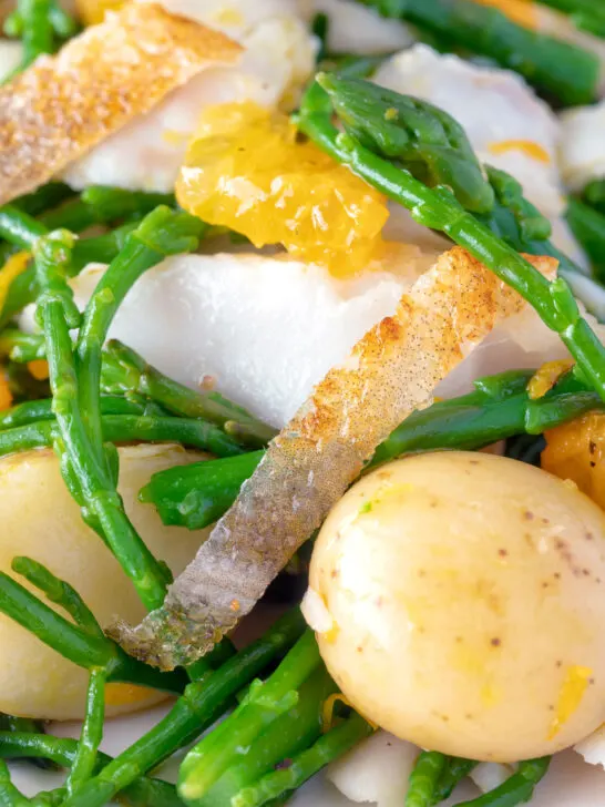 Close up cod fish salad with asparagus, samphire, new potatoes and orange.