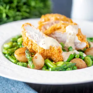 Oven baked cornflake coated chicken breast served with mustard sauce and saut&eacute;ed veggies.