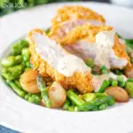 Oven baked cornflake coated chicken breast served with mustard sauce and veggies featuring a title overlay.