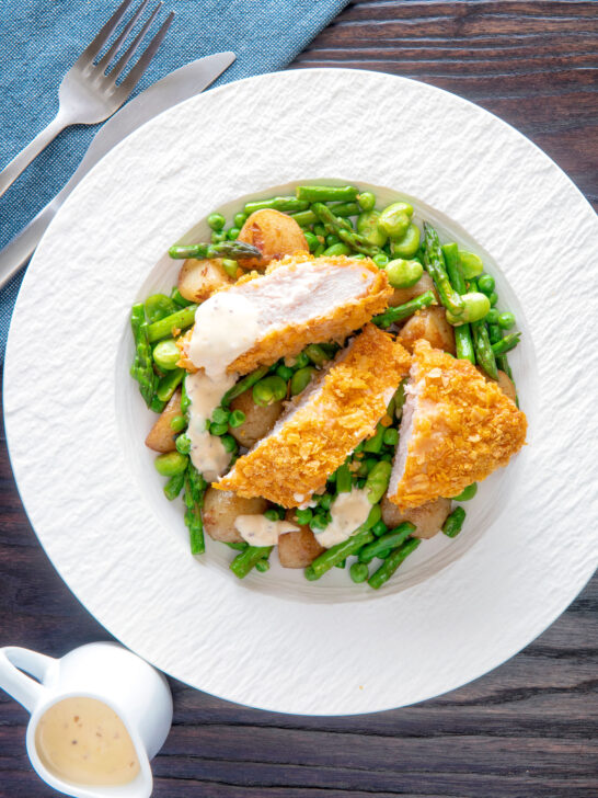 Overhead oven baked cornflake coated chicken breast served with mustard sauce and veggies.