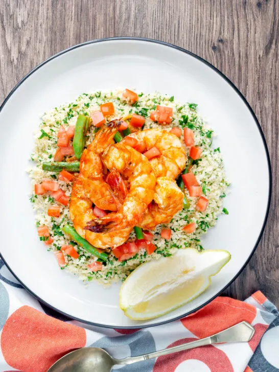 Overhead Moroccan influenced garlic harissa prawns served with couscous.