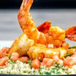 Moroccan influenced garlic harissa prawns served with couscous featuring a title overlay.