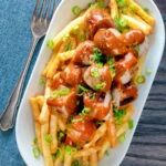 Overhead homemade German currywurst served with French fries.