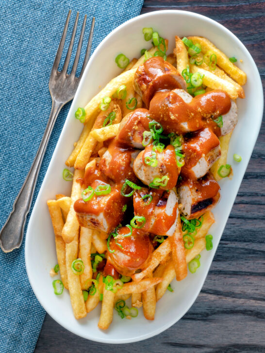 Overhead homemade German currywurst served with French fries.