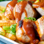 Close up homemade German currywurst with French fries featuring at title overlay.