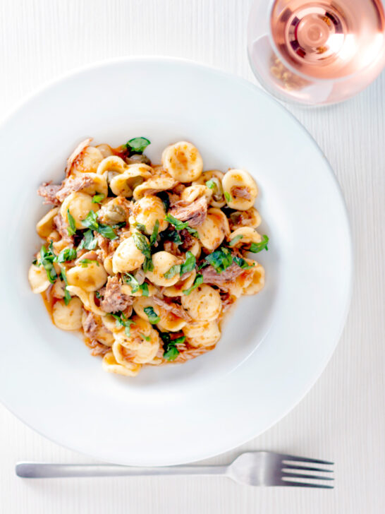 Overhead Instant Pot pork ragu with orecchiette pasta served in a white bowl.