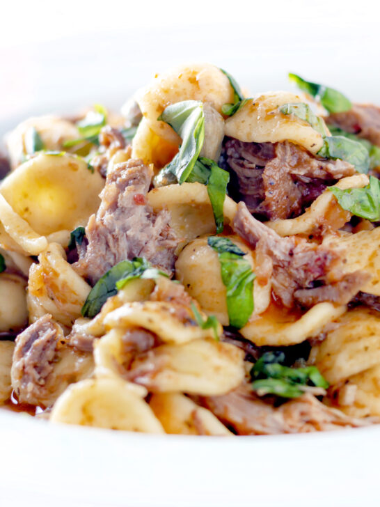 Close up Instant Pot pork ragu with orecchiette pasta served in a white bowl.