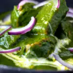 Close up palak chicken or murgh curry with red onions and cream.