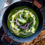 Overhead palak chicken or murgh curry with red onions and cream.
