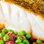 Close up pan fried cod loin with chorizo, peas and leeks.