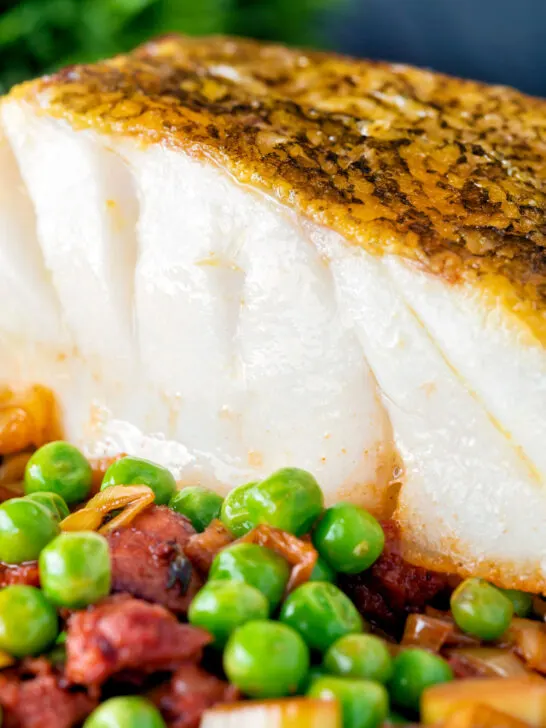 Close up pan fried cod loin with chorizo, peas and leeks.