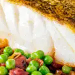 Close up pan fried cod loin with chorizo, peas and leeks featuring a title overlay.