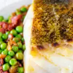Close up pan fried cod loin with crispy skin, chorizo, peas and leeks featuring a title overlay.