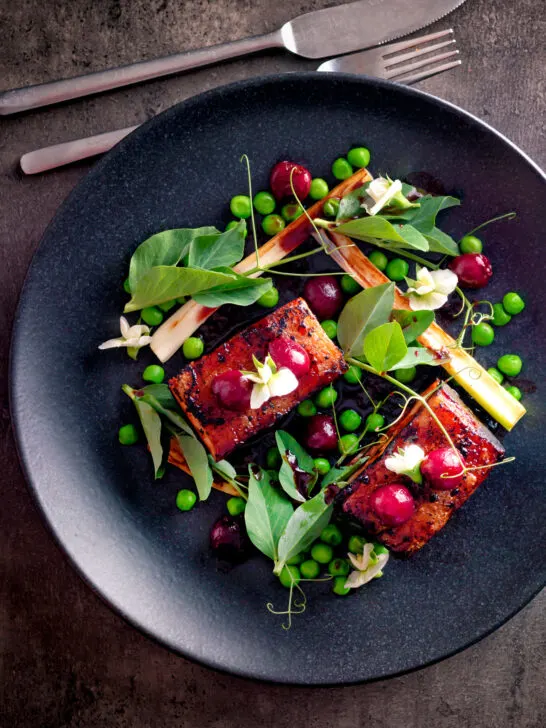 Overhead twice cooked pressed crispy pork belly with port cherries and peas.