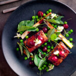 Overhead twice cooked pressed crispy pork belly with port cherries and peas featuring a title overlay.