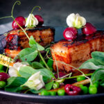 Twice cooked pressed crispy pork belly with port cherries and peas.