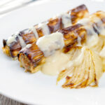 Homemade skinless sausages wrapped in charred leeks with pear and cider sauce.