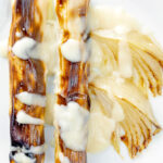 Close up overhead skinless sausages wrapped in charred leeks with pear and cider sauce.