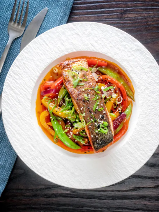 Overhead crispy skinned sweet and sour salmon fillets with vegetables.