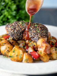 Pomegranate molasses being poured over zaatar crusted chicken legs.