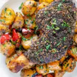 Overhead close up baked zaatar chicken legs served with spicy Lebanese potatoes featuring a title overlay.