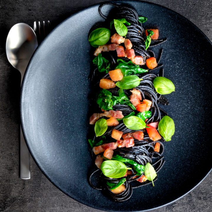 Bacon pasta with squid ink spaghetti, spinach, tomatoes and fresh basil.