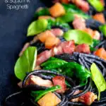 Bacon pasta with squid ink spaghetti, spinach and tomatoes featuring a title overlay.