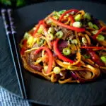 Beef noodle stir fry with sweet chilli sauce and red peppers featuring a title overlay.