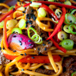 Close up Beef noodle stir fry with sweet chilli sauce and red peppers featuring a title overlay.