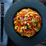 Overhead beef noodle stir fry with sweet chilli sauce and red peppers.